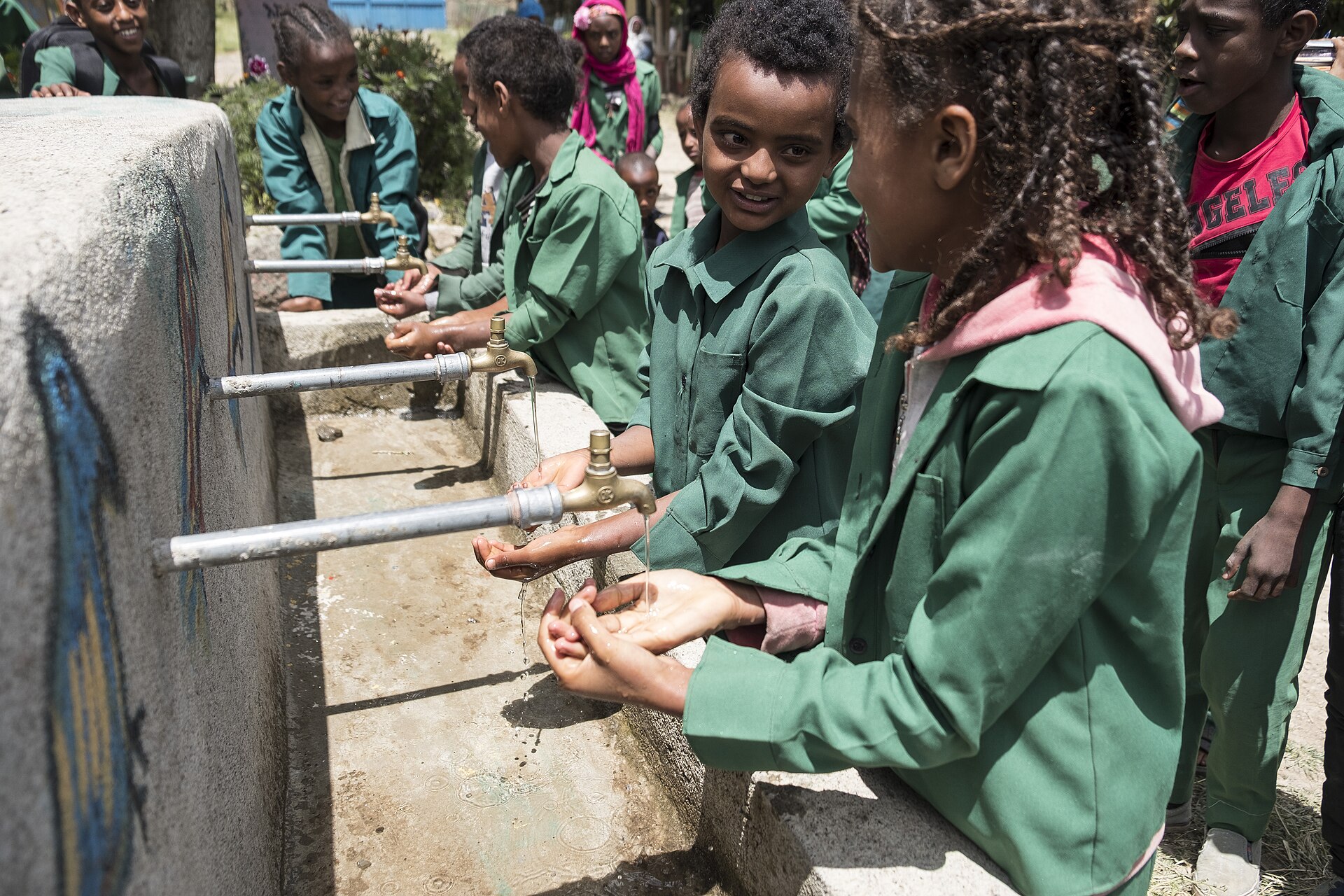 Children in school uniforms smiling at a school water point